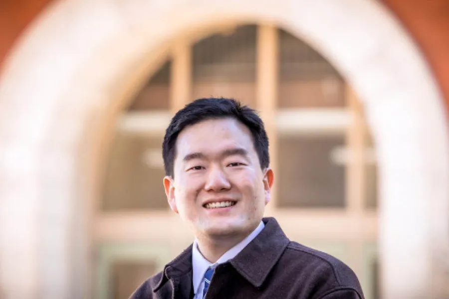 Graduate student Junghwan Kim stands in front of a building on the Illinois campus.