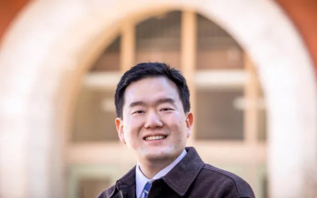 Graduate student Junghwan Kim stands in front of a building on the Illinois campus.